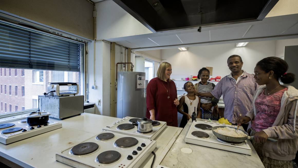 COA-medewerker in gesprek met een gezin in de keuken