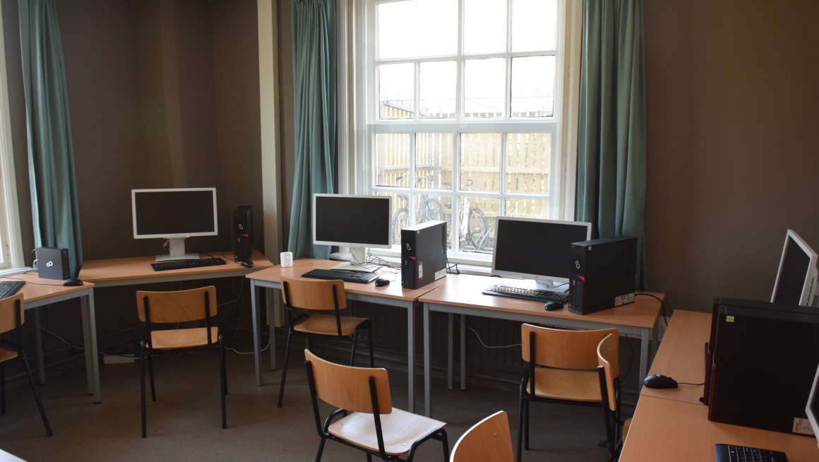 studiezaal met tafels met computers en stoelen 