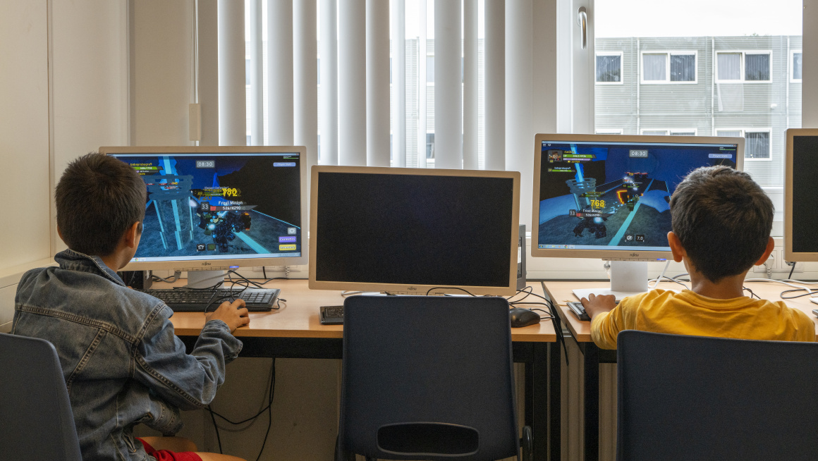 twee jongens aan het gamen in het open leercentrum voor een raam met witte lamellen