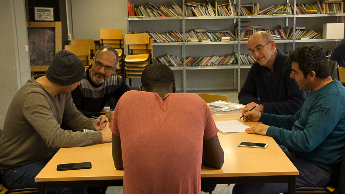 mannen krijgen les aan een tafel in de bibliotheek