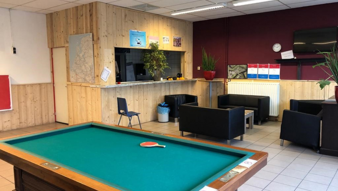 Recreatieruimte met bar, zwarte bankjes en biljarttafel