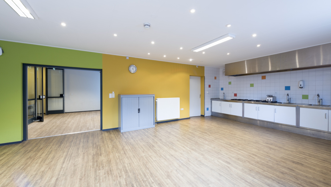keuken met vloer met houtnerf gele en groene muur en een muur met witte tegels met af en toe een gekleurde tegel