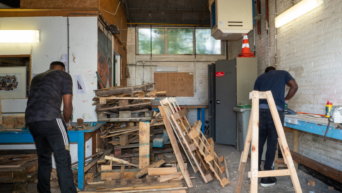 Bewoners in werkplaats met hout aan het klussen