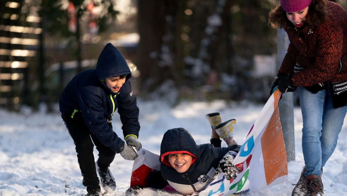 Asielzoekersinderen spelen buiten in de sneeuw 