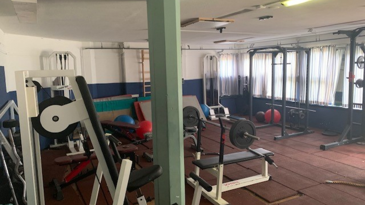 Fitnesssruimte met fitnessaparatuur, matten, gekleurde ballen en ramen met vitrage