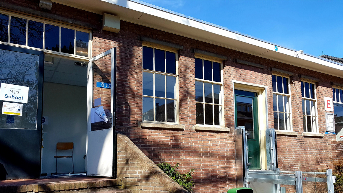 open leercentrum, gebouw met trap en daarnaast een liftje voor minder validen en daartussen een grijze prullenbak met groene bovenkant