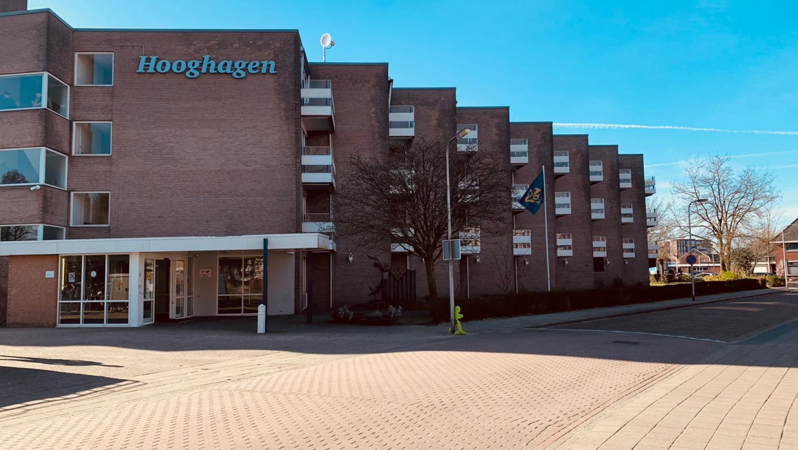 voorkant en ingang gebouw met witte balkons en straat ervoov