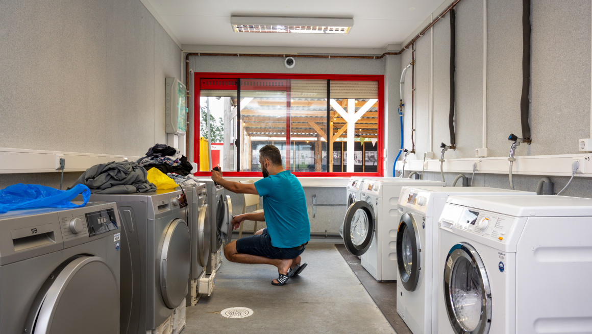 Een man doet zijn was in de ruimte met wasmachines en drogers.