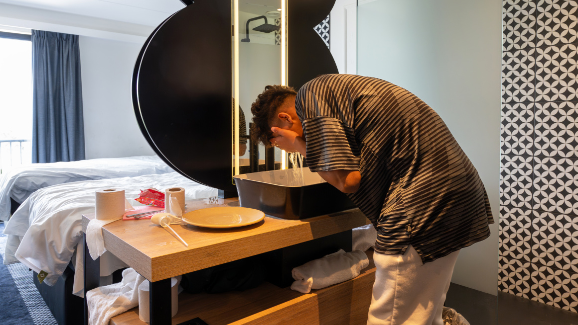 Minderjarige asielzoeker is in zijn slaapkamer bij de wasbak zijn gezicht aan het wassen
