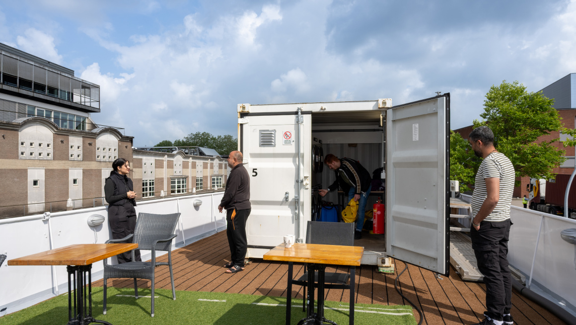 In de container op het dek van het schip doet een man de was. 