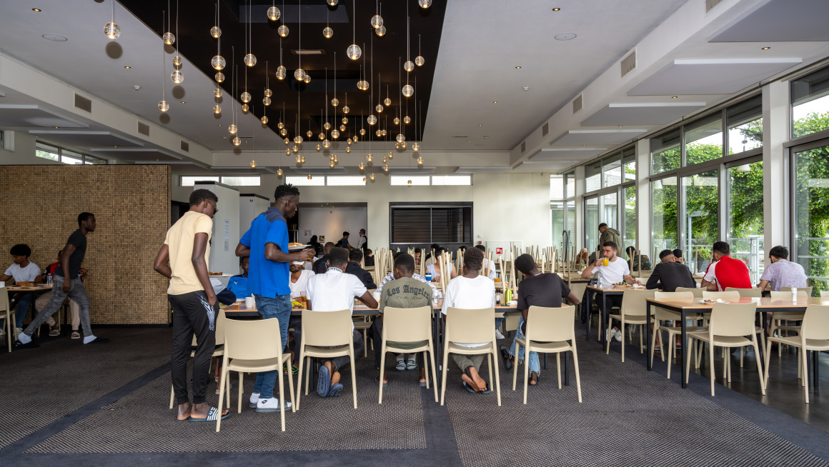 De eetzaal zit vol met minderjarige jongens die aan het lunchen zijn.