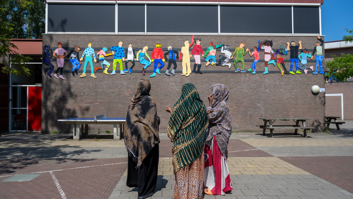 3 minderjarige meisjes staan op het schoolplein bij de noodopvang.