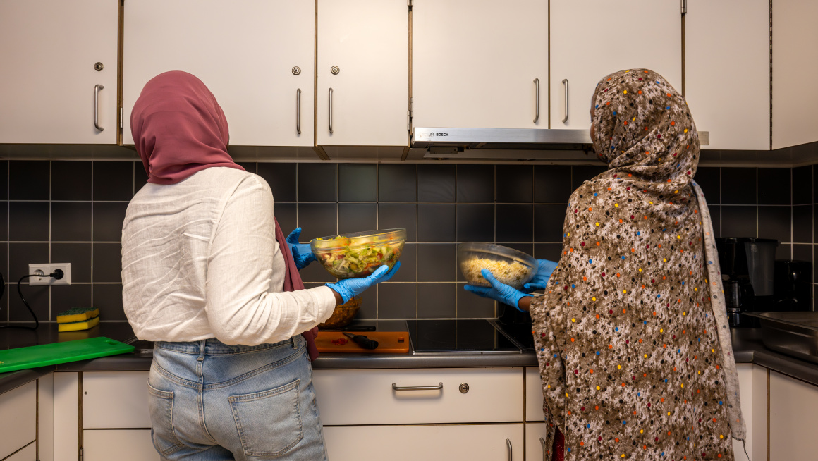 2 minderjarige meisjes maken eten klaar in de keuken.