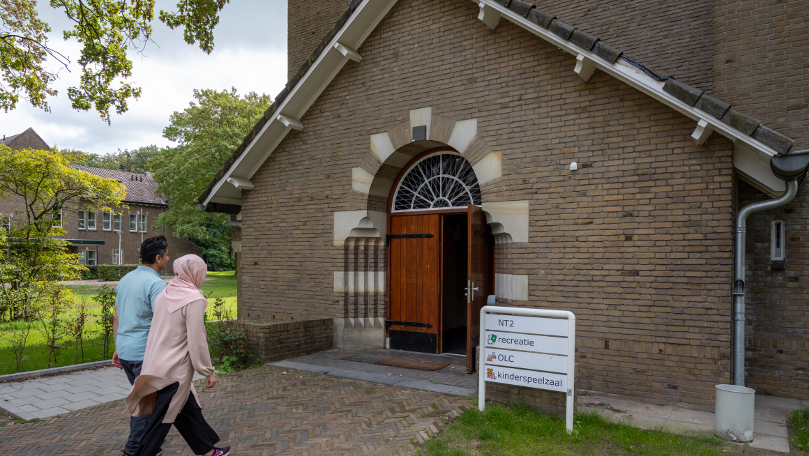 Man en vrouw lopen richting de ingang van de kapel van azc Apeldoorn