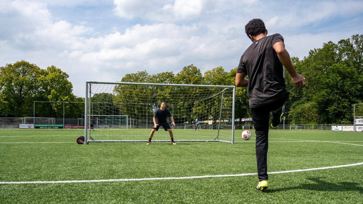 Voetballer schiet bal in doel