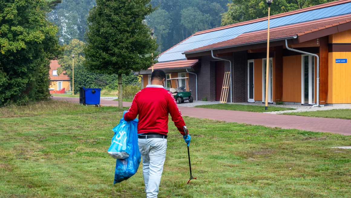 Asielzoeker raapt zwerfafval op coa locatie Luttelgeest