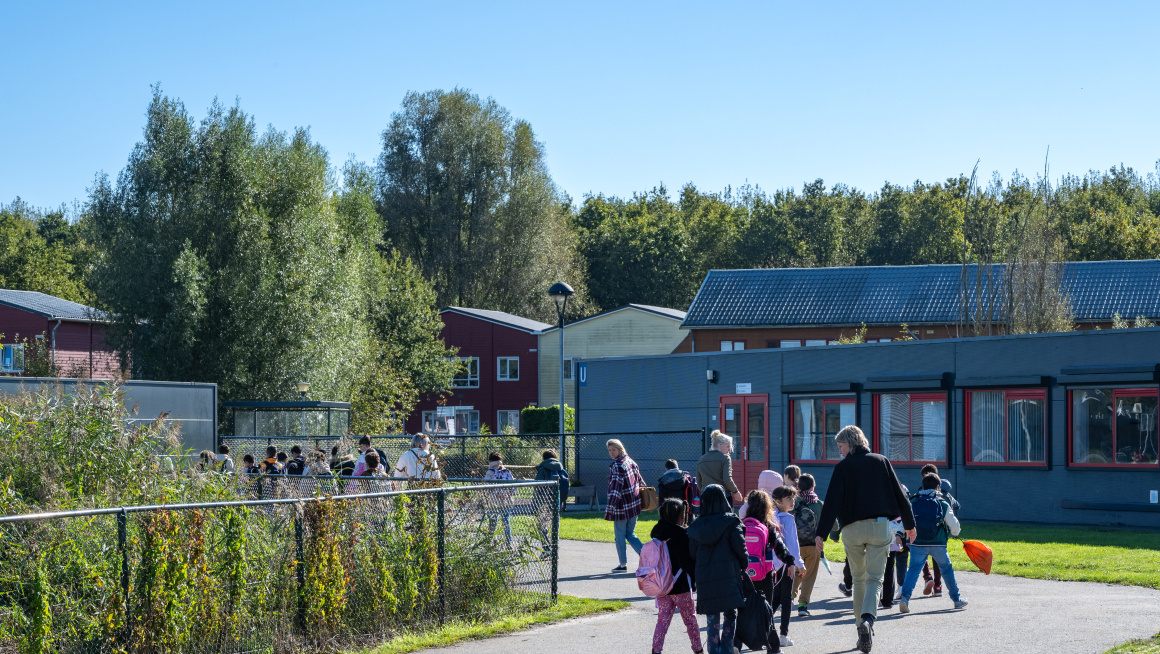 Kinderen lopen onder begeleiding over het terrein in het azc Zeewolde