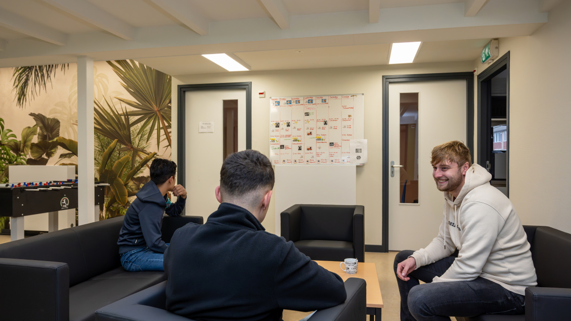 Amv jongeren in de woonkamer in gesprek met woonbegeleider