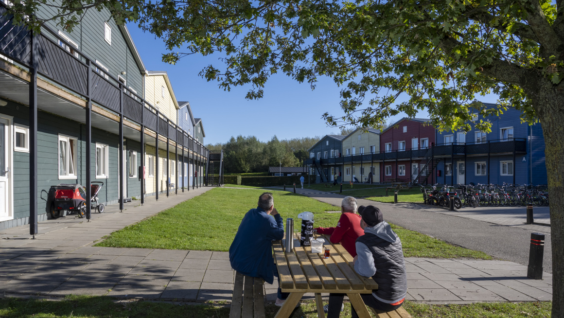 3 bewoners aan een picknicktafel op binnenplaats van opvanglocatie