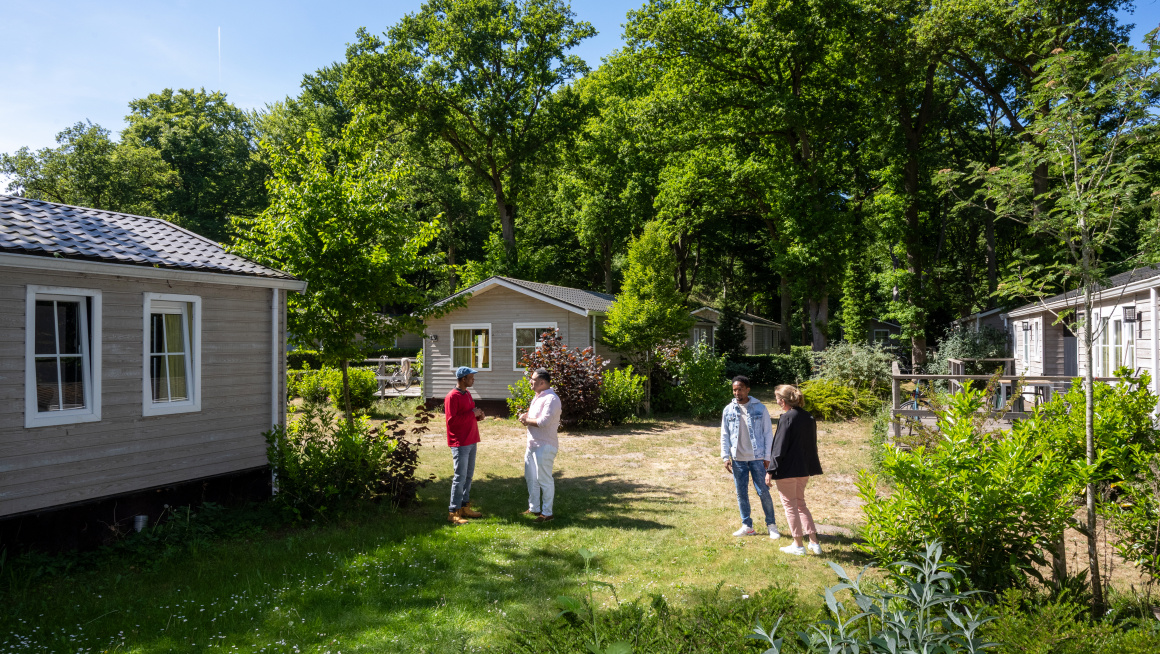 huisjes op coa locatie wassenaar duinrell, bewoners en begeleiders staan in de tuin met elkaar te praten