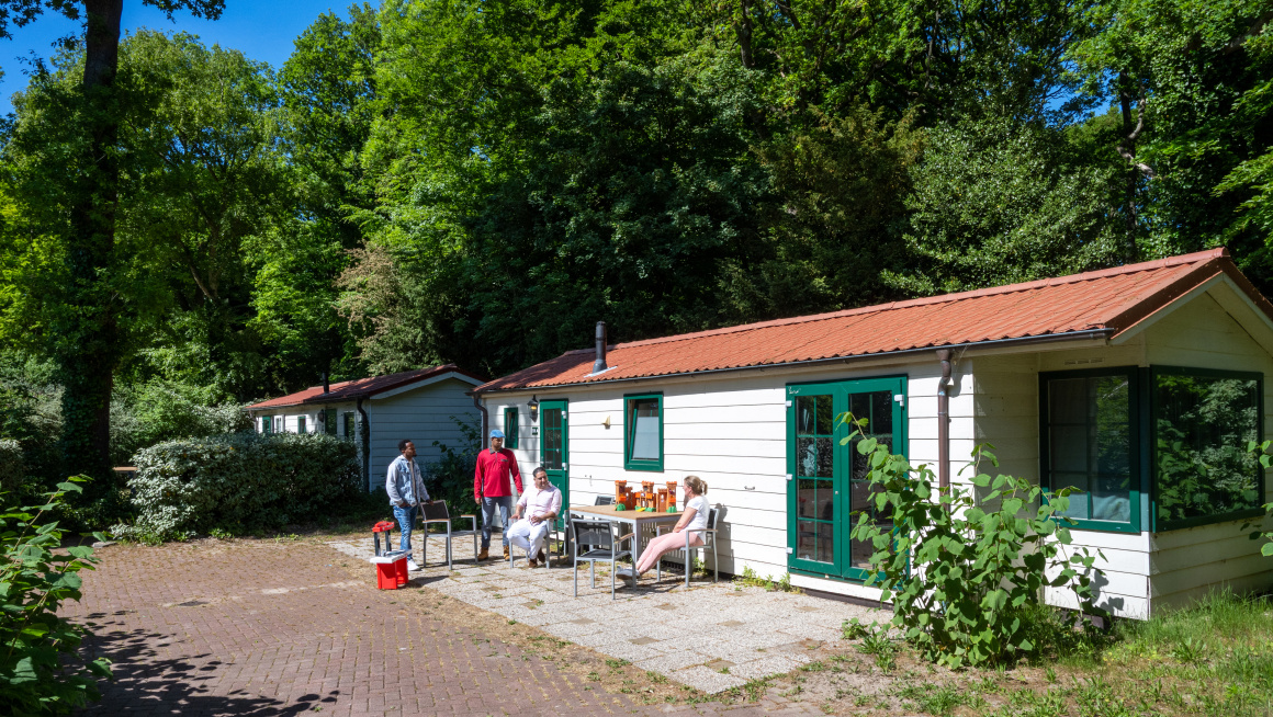 bewoners en begeleider zitten voor hun huisje in wassenaar duinrell