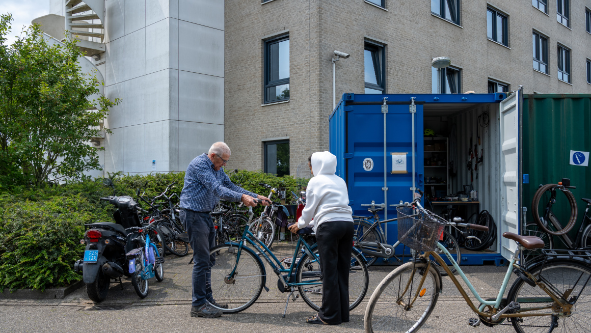 vrijwilliger helpt bewoner met repareren van de fiets