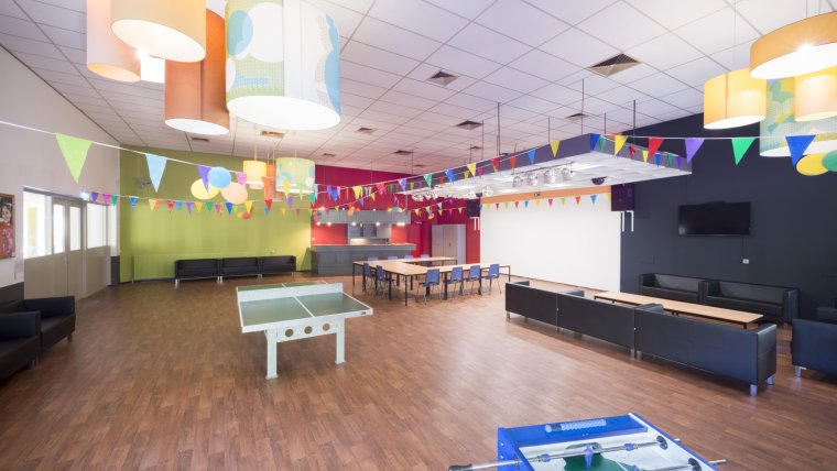 recreatiezaal met tafeltennis- en voetbaltafel en gekleurde vlaggetjes