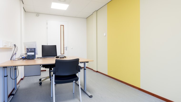 Spreekkamer met bureau en twee zwarte stoelen