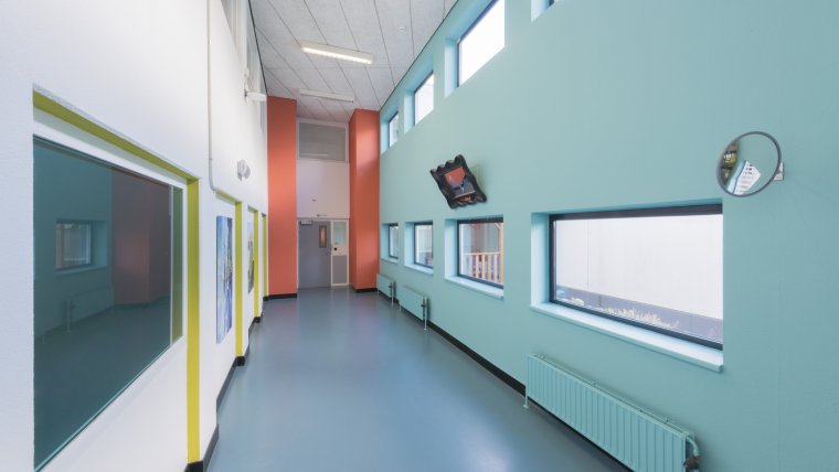 gang met ramen, blauwe vloer, blauwe muur en witte muren met gele en oranje accenten