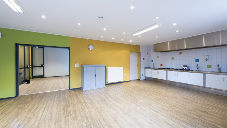 keuken met vloer met houtnerf gele en groene muur en een muur met witte tegels met af en toe een gekleurde tegel