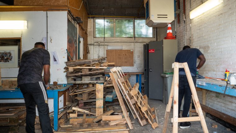 Bewoners in werkplaats met hout aan het klussen