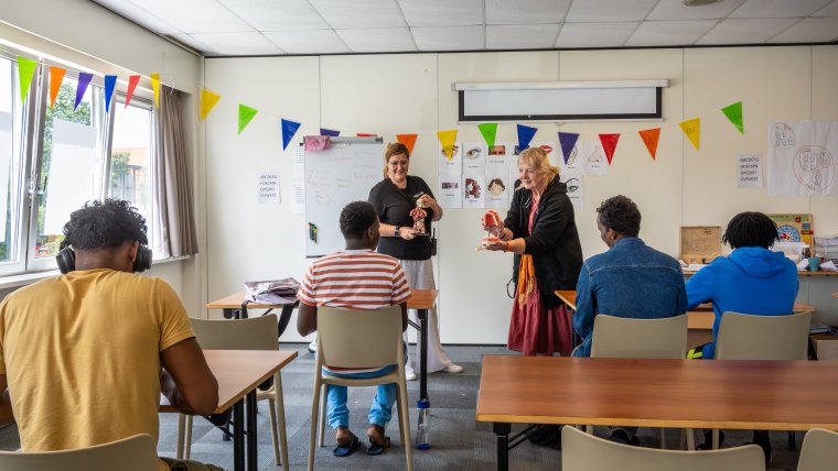 4 asielzoekers leren in een klaslokaal van twee vrijwilligsters over gezondheid