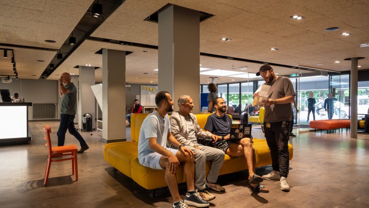 Statushouders in gesprek met een medewerker in de hal van de noodopvang.