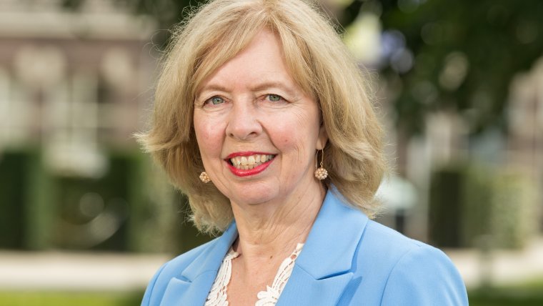 wethouder draagt blauw jasje met witte blouse, grote lach