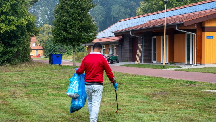 Asielzoeker raapt zwerfafval op coa locatie Luttelgeest