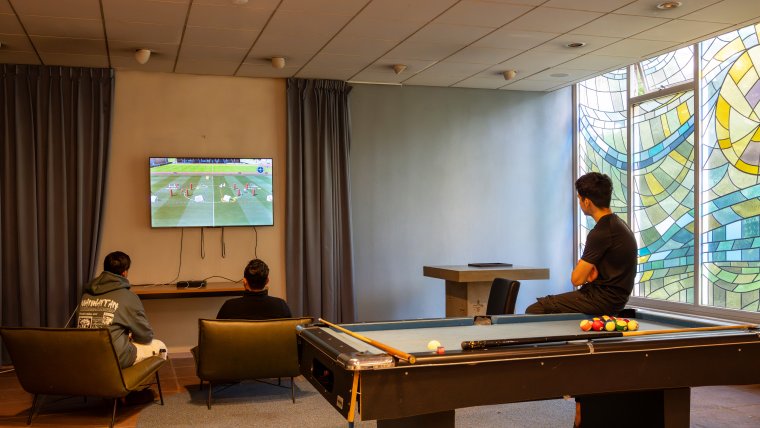 Jonge asielzoekers kijken tv in de recreatieruimte van het azc