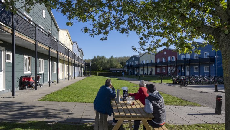 3 bewoners aan een picknicktafel op binnenplaats van opvanglocatie