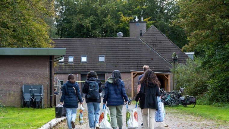 Jongeren die lopen op azc-locatie met boodschappentassen