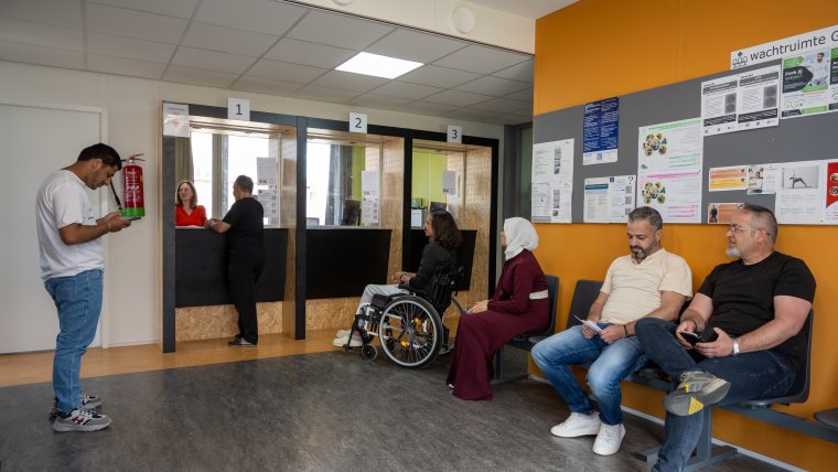 bewoners zitten te wachten op hun beurt bij de infobalie