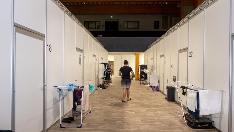 een gang met links en rechts gebouwde kamers voor asielzoekers, er staan wasrekjes in de gang