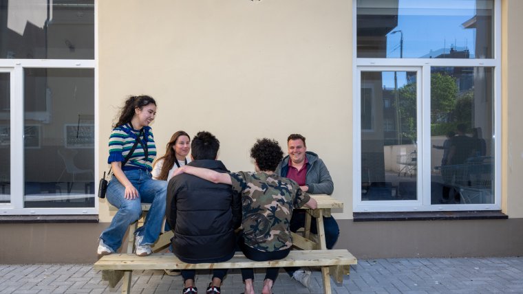 begeleiders en bewoners aan de picknicktafel buiten Den Haag Gevers Deynootweg