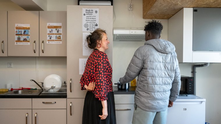 begeleider in gesprek met bewoner in de keuken van Den Haag Gevers Deynootweg
