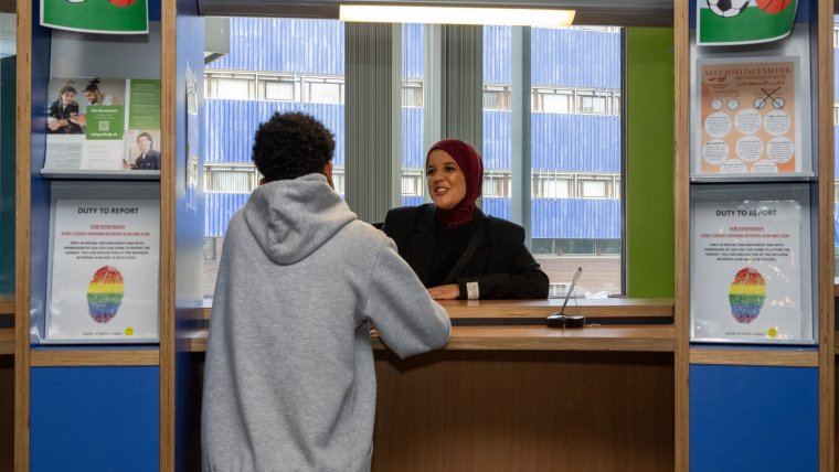 medewerkster staat asielzoeker te woord aan de infobalie