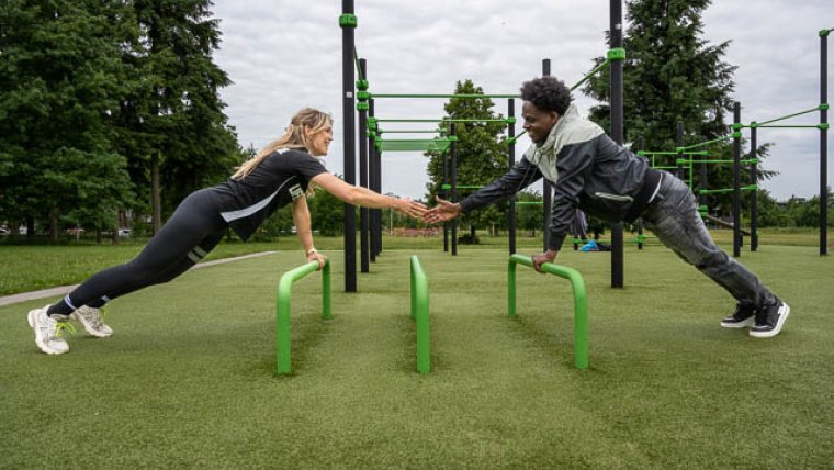 sportcoach en deelnemer sport leunend op attribuut buiten 
