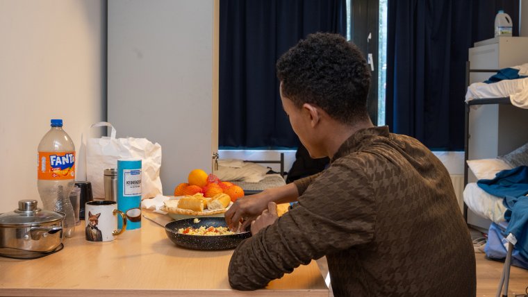 bewoner eet zijn maaltijd aan tafel op zijn slaapkamer