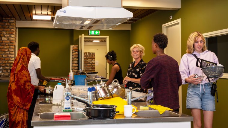 Bewoners en begeleiders in de keuken van Serooskerke doen de afwas
