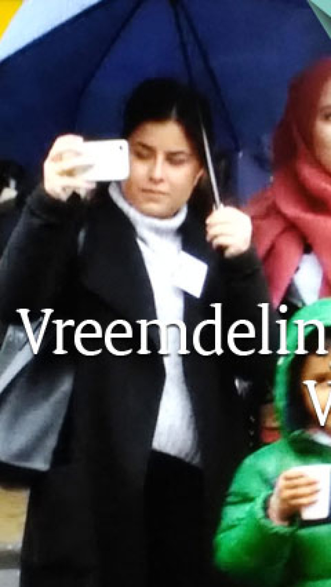 2 sames staan onder een paraplu en ook een kind met een beker