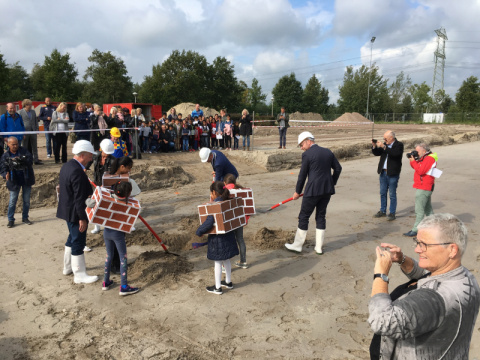 Kinderen verkleed als bakstenen graven het eerste gat