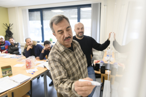 Statushouder schrijft op whiteboard tijdens les Kennis van de Nederlandse Maatschappij