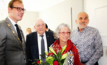 Vrouw poseert met de burgemeester en een bos bloemen